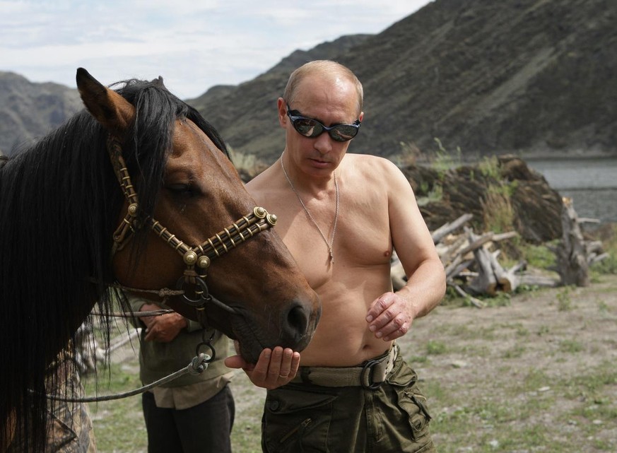 In this photo taken on Monday, Aug. 3, 2009, Russian Prime Minister Vladimir Putin seen feeding a horse in the mountains of the Siberian Tyva region (also referred to as Tuva), Russia, during his shor ...