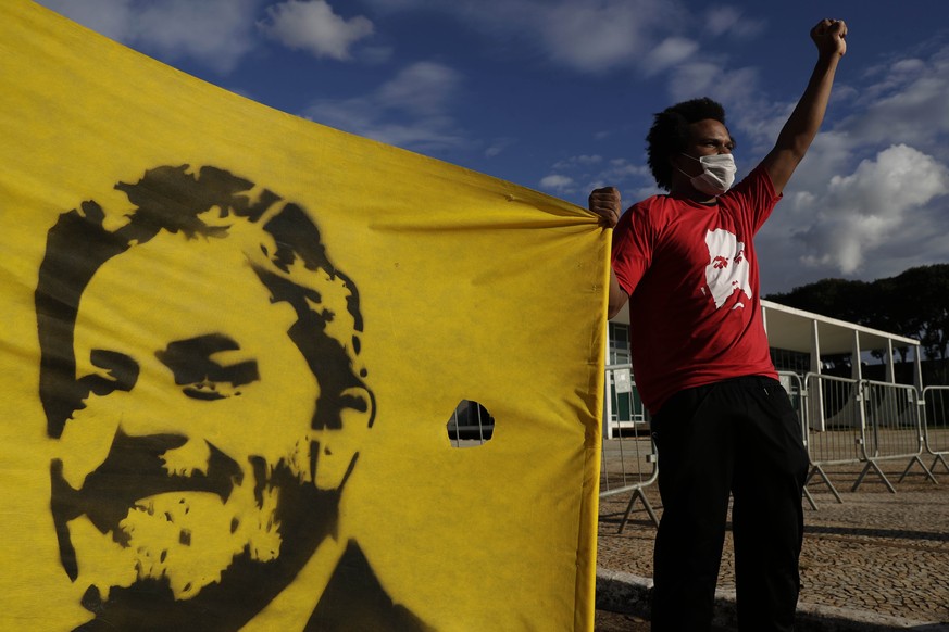A Worker Party member shows his support during a demonstration outside the Supreme Court while holding on to a banner featuring Brazil&#039;s former President Luiz Inacio Lula da Silva, in Brasilia, B ...