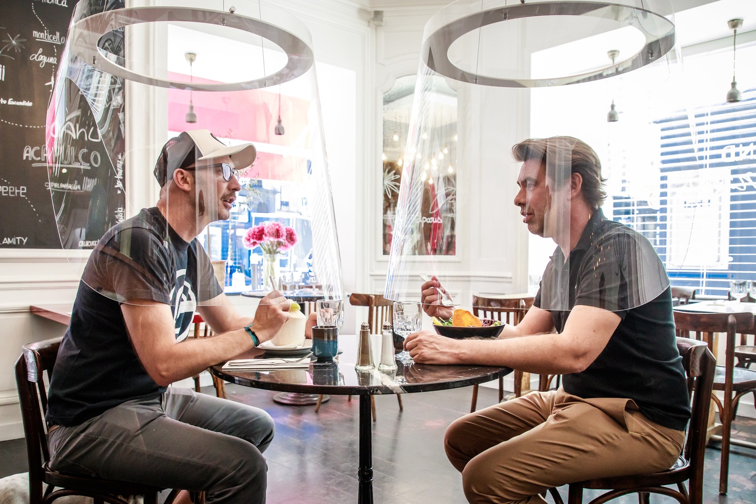 epa08449677 French Designer Christophe Gernigon (R) tries out his creation Plex&#039;Eat, plexiglas bubble which surrounds customers to protect them from the covid-19 infection during a press presenta ...