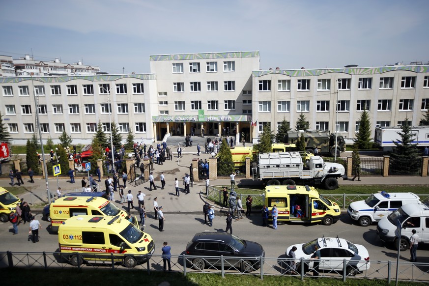 Ambulances and police cars and a truck are parked at a school after a shooting in Kazan, Russia, Tuesday, May 11, 2021. Russian media report that several people have been killed and wounded in a schoo ...