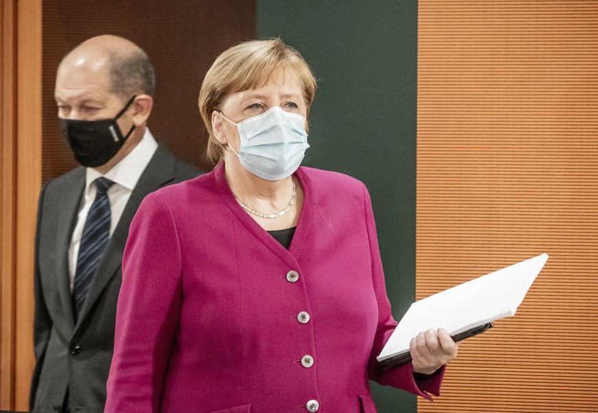 German Chancellor Angela Merkel, right, and Vice-Chancellor Olaf Scholz, left, wear face masks as they arrive for the weekly cabinet meeting at the Chancellery in Berlin, Germany, Wednesday, Oct. 14,  ...