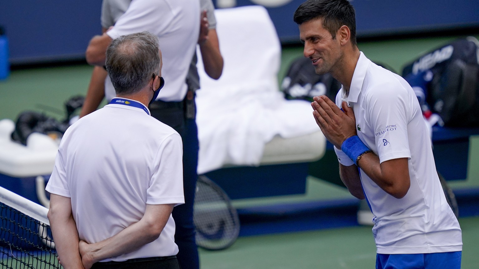 Novak Djokovic, of Serbia, talks with the umpire after inadvertently hitting a line judge with a ball after hitting it in reaction to losing a point against Pablo Carreno Busta, of Spain, during the f ...