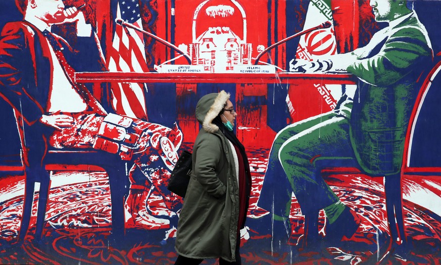 epa08859344 An Iranian woman walks past next to an anti-US mural iin a street in Tehran, Iran, 03 December 2020. Iranian president Rouhani said that his government does not agree with the parliament&# ...