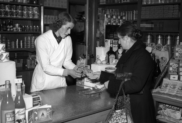 Eine Frau bezahlt im Lebensmittelgeschaeft mit Rationierungsmarken, aufgenommen im Maerz im Kriegsjahr 1942. Aufgrund der schwachen Wirtschaftslage im Krieg werden Lebensmittel und andere Gueter knapp ...