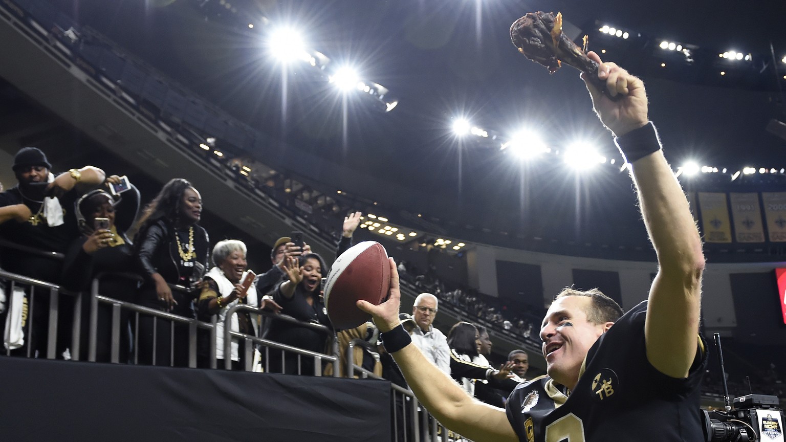 New Orleans Saints quarterback Drew Brees (9) responds to the fans with a turkey drumstick as he runs off the field Thanksgiving night after an NFL football game against the Atlanta Falcons in New Orl ...