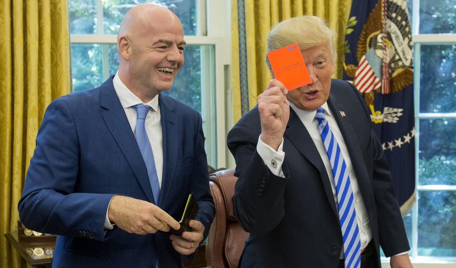 epa06979412 US President Donald J. Trump (R) holds up a FIFA red card that has his name on it, toward members of the news media, given to him by President of FIFA Gianni Infantino (L) during their mee ...