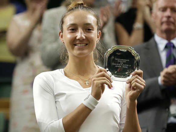 Leonie Kung of Switzerland holds up the runner up trophy after being defeated by Iga Swiatek of Polans in their girls&#039; singles final at the Wimbledon Tennis Championships, in London, Saturday Jul ...
