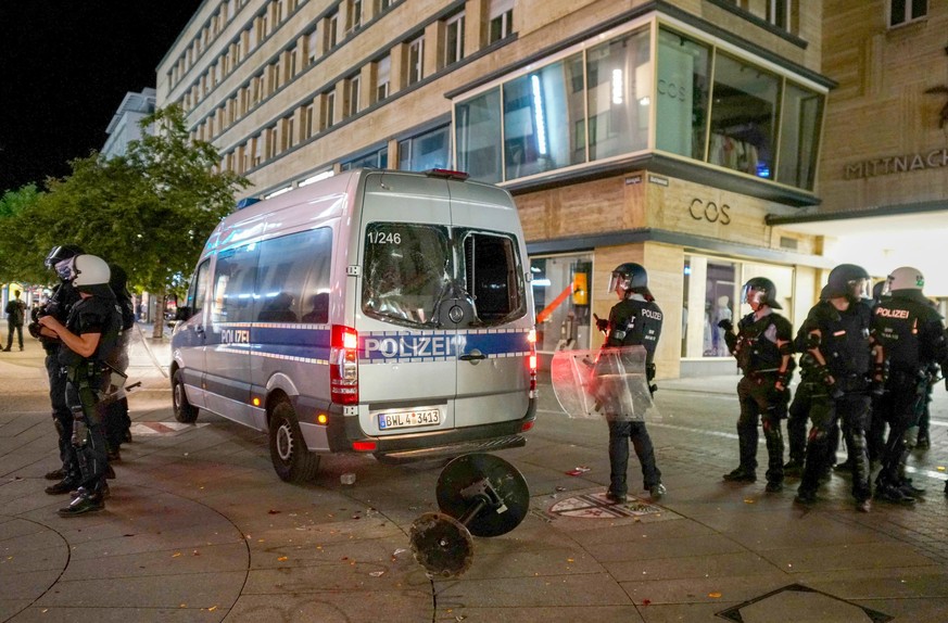 epa08500386 Police officers stand next to a damaged police car in the downtown shopping area of Stuttgart, southern Germany, 21 June 2020. According to local police, several hundreds of rioting youths ...