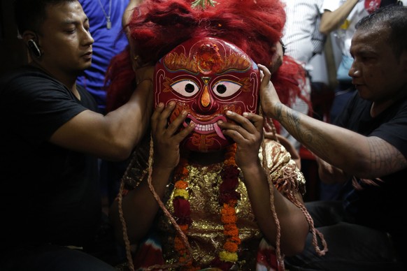 A traditional mask dancer, known as Lakhe, gets dressed for the Indra Jatra festival in Kathmandu, Nepal, Tuesday, Sept. 5, 2017. Indra is considered the Hindu god of rain and the festival marks the e ...