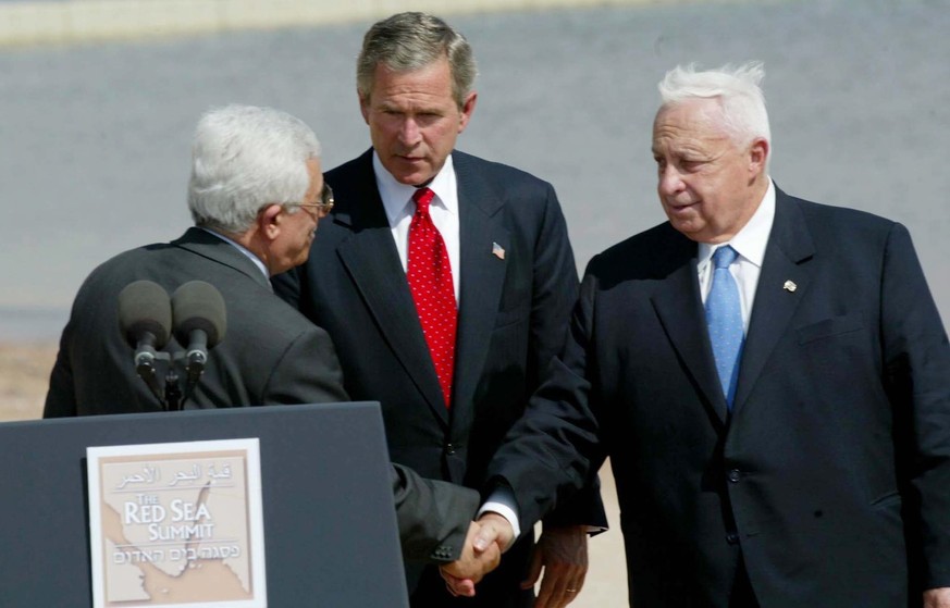 US President George W. Bush (C) looks on as Israeli Prime Minister Ariel Sharon (R) and Palestinian Prime Minister Mahmoud Abbas shake hands on Wednesday, June 4, 2003 in Aqaba. Jordan is hosting the  ...