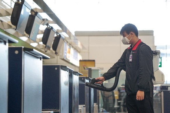 epa08387103 A handout photo made available by Hong Kong International Airport shows a worker spraying disinfectant on check-in counters in the departure hall of Hong Kong International Airport in Hong ...