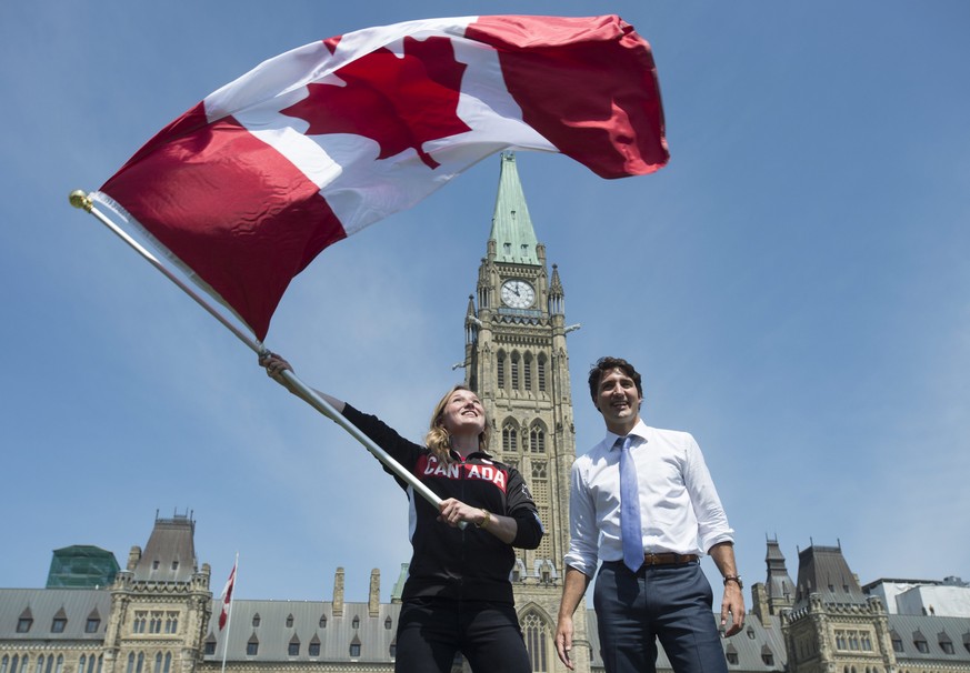 Canada&#039;s Prime Minister Justin Trudeau looks on as athlete Rosie MacLennan waves the Canadian flag after being named as the flag bearer for the upcoming Summer Olympics Thursday July 21, 2016 in  ...