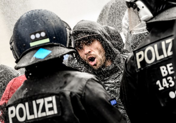 epa08827860 Police officers struggle with protesters while breaking up a demonstration against German coronavirus restrictions, near the Brandenburg Gate in Berlin, Germany, 18 November 2020. While Ge ...