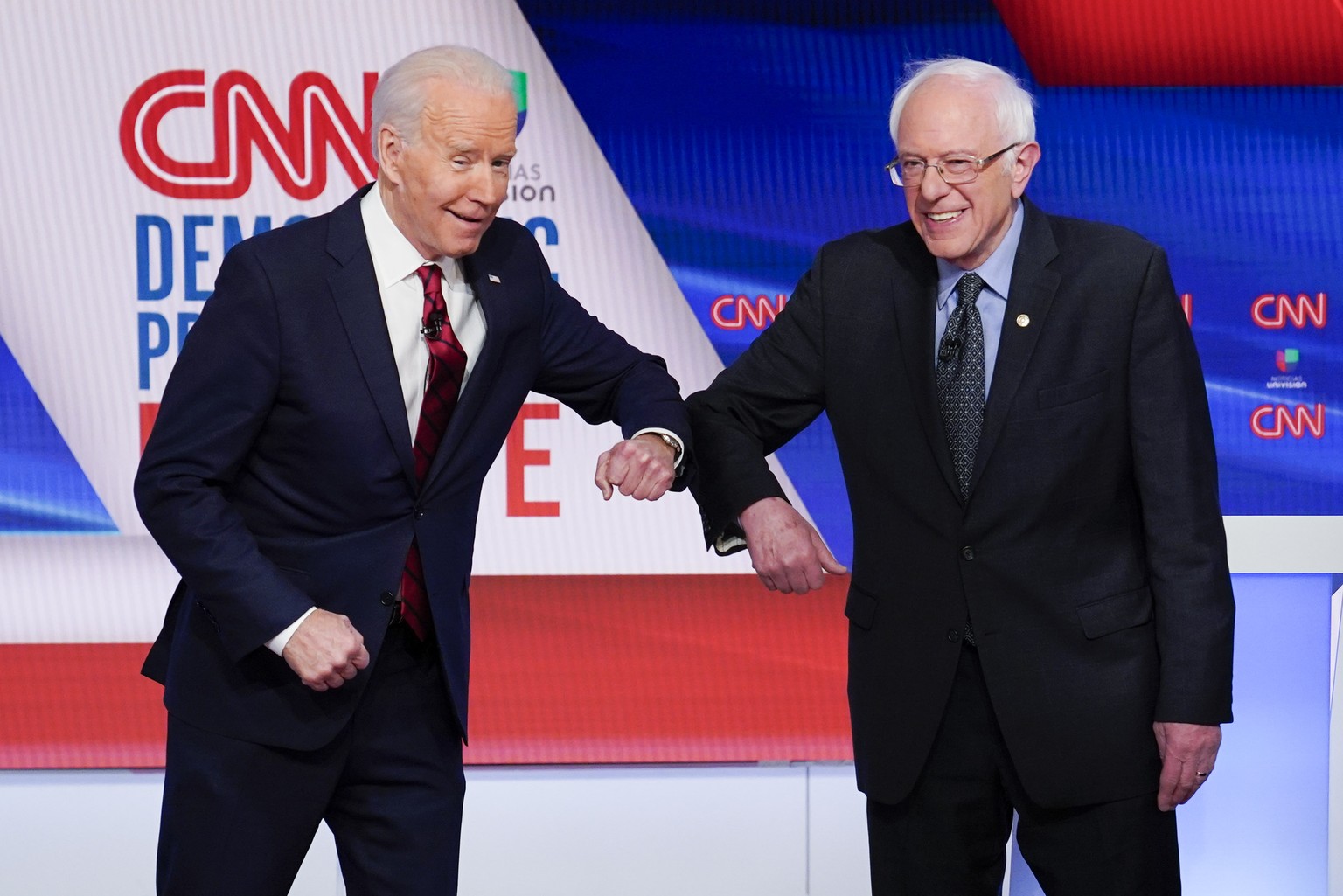 Former Vice President Joe Biden, left, and Sen. Bernie Sanders, I-Vt., right, greet each other before they participate in a Democratic presidential primary debate at CNN Studios in Washington, Sunday, ...
