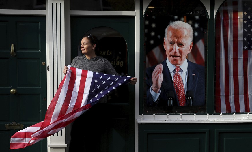 Catherine Hallahan, owner of Hallihan&#039;s barbers holds a US flag, as residents begin celebrations in the ancestral home of Joe Biden in anticipation of the results of the US election, in Ballina,  ...