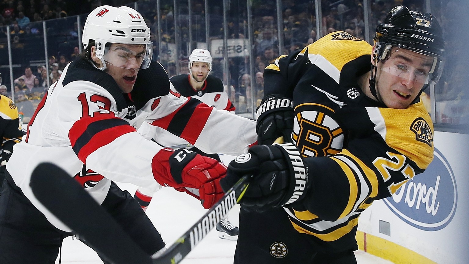 Boston Bruins&#039; John Moore (27) and New Jersey Devils&#039; Nico Hischier (13) battle along the boards during the first period of an NHL hockey game in Boston, Saturday, March 2, 2019. (AP Photo/M ...