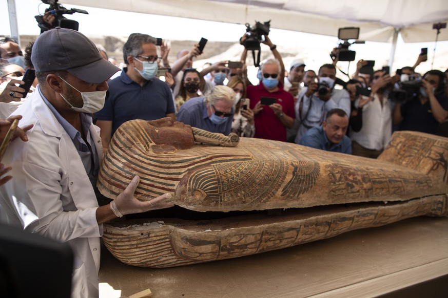 An archaeology worker opens a sarcophagus at the Saqqara archaeological site, 30 kilometers (19 miles) south of Cairo, Egypt, on Saturday, Oct. 3, 2020, in the presence of journalists and officials. E ...