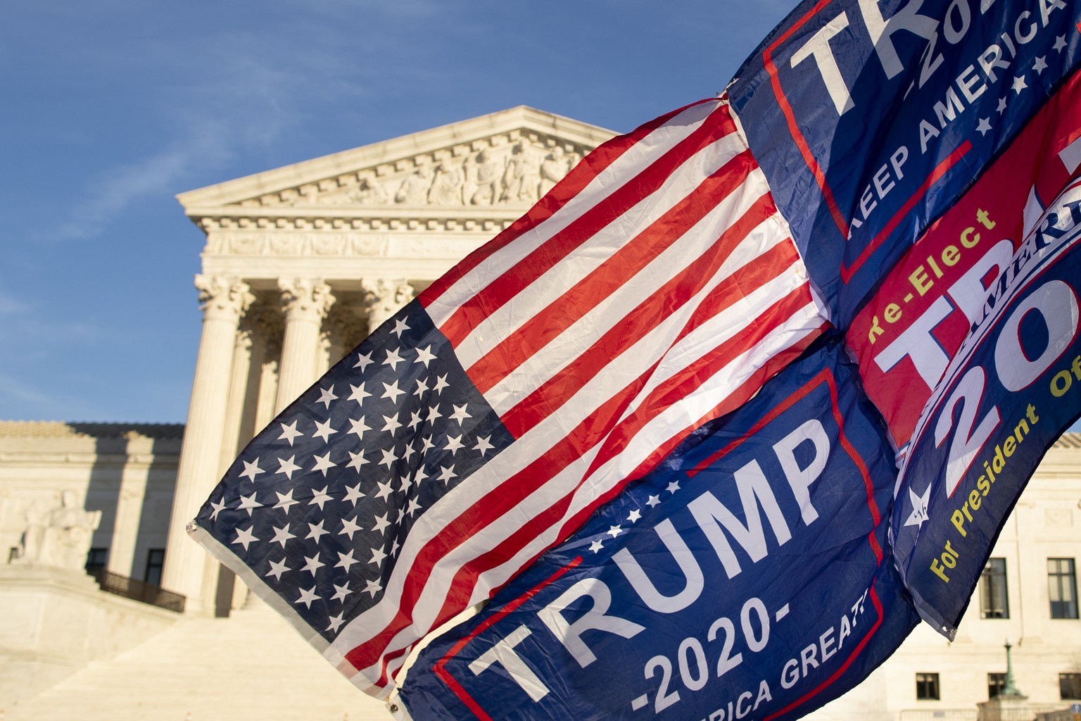 epa08878237 A supporter of US President Donald J. Trump holds a flag outside the Supreme Court in Washington, DC, USA, 11 December 2020. One hundred twenty-six House Republicans, including House Minor ...