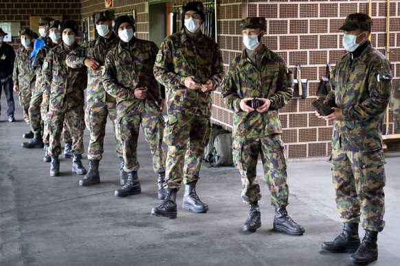 Soldiers of the Swiss army wearing protective face mask during a rifle shooting exercise with smartphone in their pocket during a test, with 100 soldiers, of a smart phone app using Decentralized Priv ...