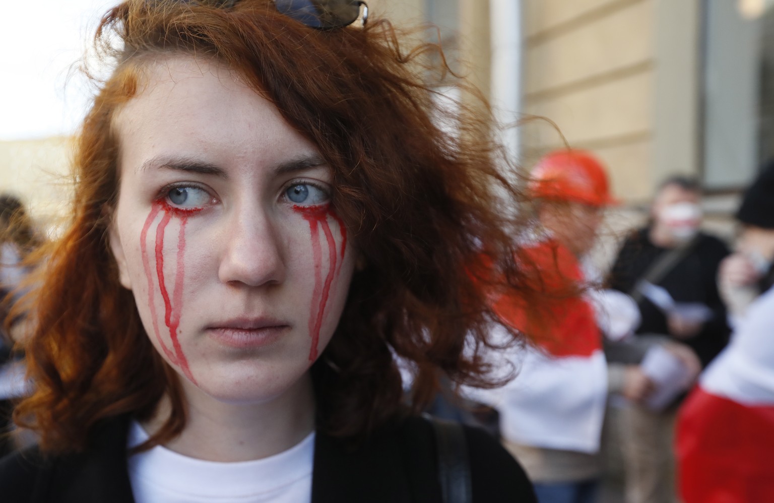 epa08681821 A young woman painted tears in colors of the historic Belarusian flag on her face as she attends a rally in solidarity with the Belarusian people, following recent protests to reject the p ...