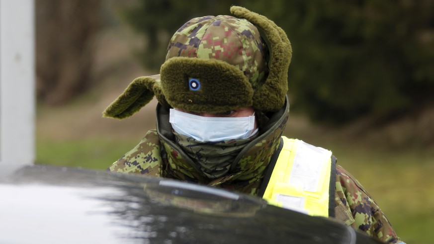 epa08301296 Estonian Defence League member is checking documents at the Valga-Valka border crossing point, Latvia, 17 March 2020. Estonian government has declared an emergency situation due to coronav ...