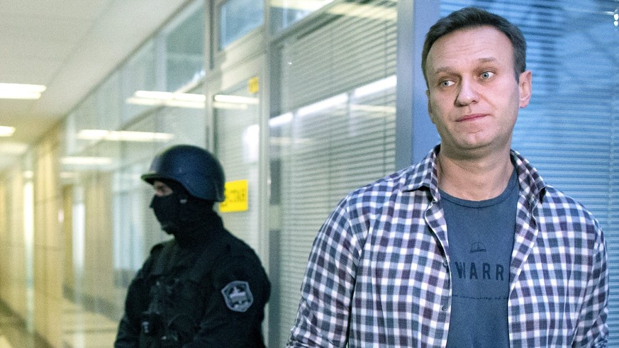 FILE- In this Dec. 26, 2019, file photo, Russian opposition leader Alexei Navalny speaks to the media in front of a security officer standing guard at the Foundation for Fighting Corruption office in  ...