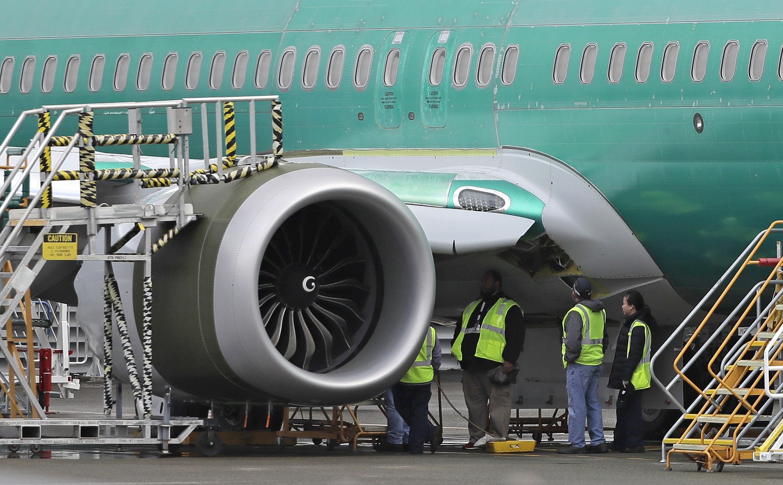 Workers stand next to a engine of a Boeing 737-MAX 8, Wednesday, Nov. 14, 2018, at Boeing Co.&#039;s 737 assembly facility in Renton, Wash. Boeing didn&#039;t tell airline pilots about features of a n ...