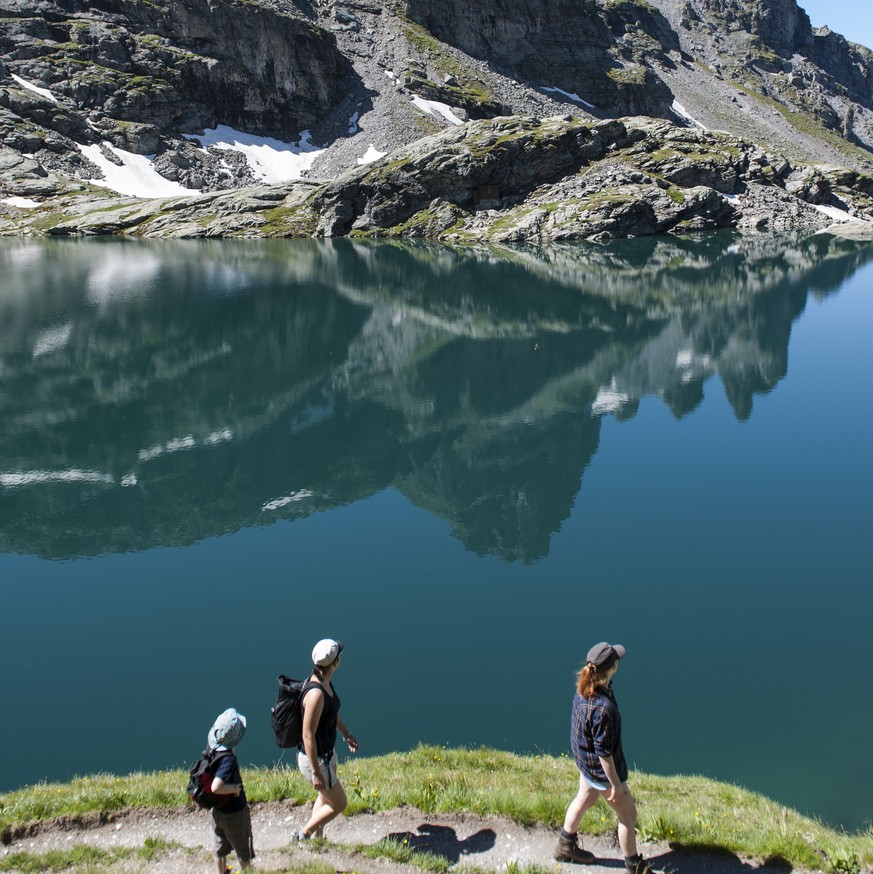 Wanderer blicken auf den Schottensee und den darueber thronenden Hochwart, auf der Fuenf Seen Wanderung, in Wangs-Pizol, am Mittwoch, 16. Juli 2014. (KEYSTONE/Gian Ehrenzeller)