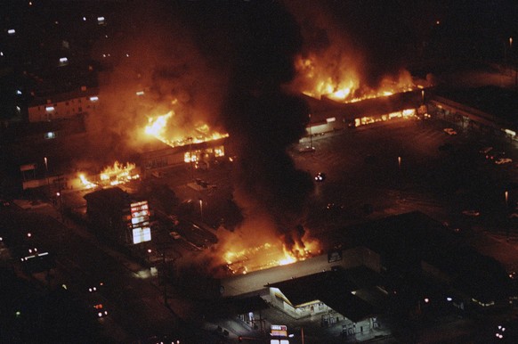 FILE - In this Wednesday, April 30, 1992 file photo, several buildings in a shopping center are engulfed in flames before firefighters arrive as rioting continued in South-Central Los Angeles in the a ...