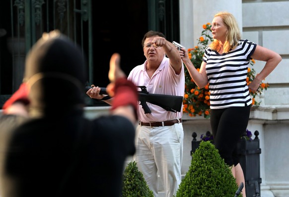 FILE - In this June 28, 2020 file photo, armed homeowners Mark and Patricia McCloskey, standing in front their house along Portland Place confront protesters marching to St. Louis Mayor Lyda Krewson&# ...