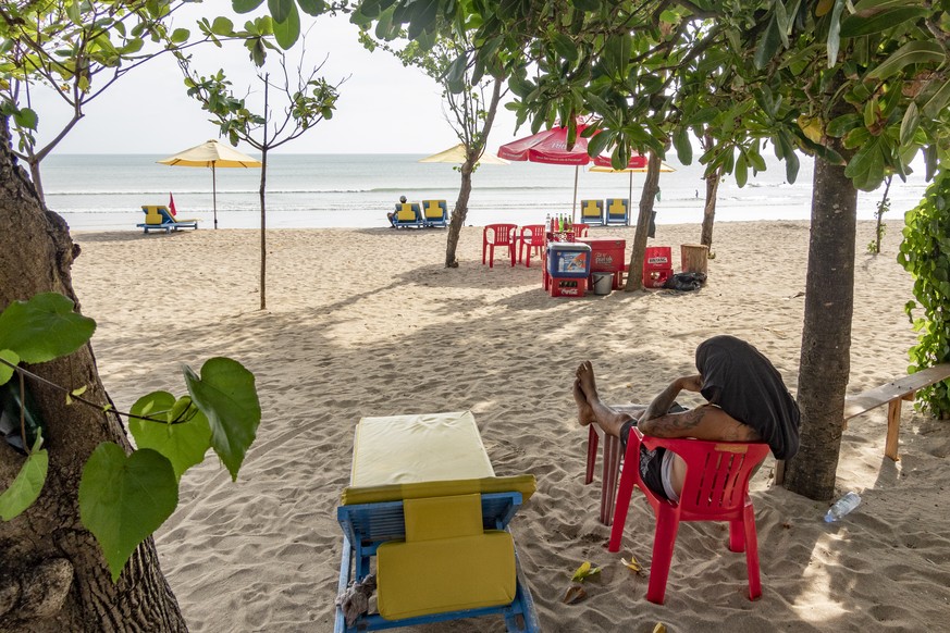 epa09198900 A drink vendor waits for customers at a beach in Kuta, Bali, Indonesia, 14 May 2021. The Indonesian government strictly prohibits people to travel during Eid al-Fitr holiday from 06 to 17  ...