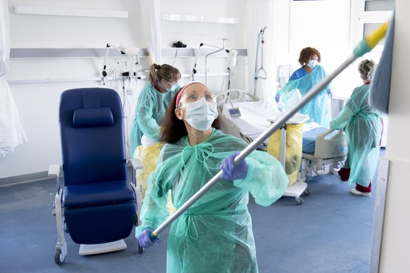 epa08318874 Hygiene workers clean and disinfect a room for coronavirus patients in the Covid-19 unit of the hospital &#039;Reseau hospitalier neuchatelois (RHNe)&#039; site during the coronavirus dise ...
