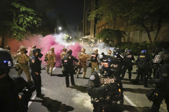 Police respond to protesters during a demonstration, Friday, July 17, 2020 in Portland, Ore. Militarized federal agents deployed by the president to Portland, fired tear gas against protesters again o ...