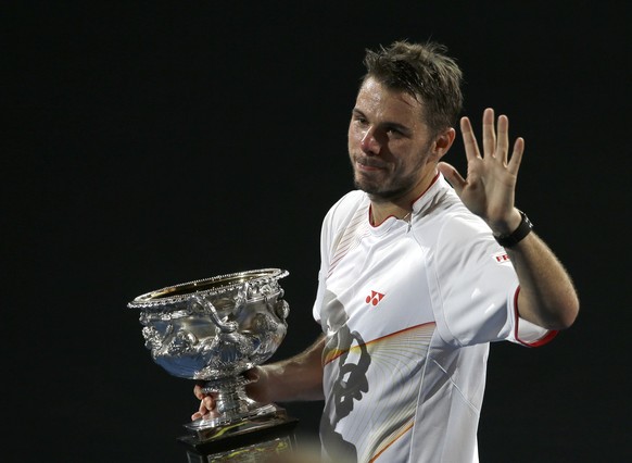 Stanislas Wawrinka of Switzerland walks around the court, with the trophy after defeating Rafael Nadal of Spain in the men&#039;s singles final at the Australian Open tennis championship in Melbourne, ...