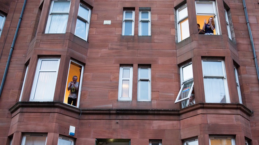 epa08339632 People in Partick, Glasgow clap from their windows at 8pm in recognition of the work done by the National Health Service (NHS), in Glasgow, Scotland, Britain, 02 April 2020. Countries arou ...
