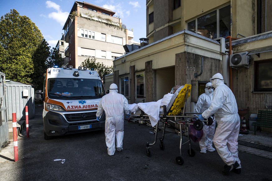 epa08339365 Paramedics clad in hazmat suits carry a stretcher with a patient infected with the pandemic COVID-19 disease caused by the SARS-CoV-2 coronavirus to an ambulance in Rome, Italy, 02 April 2 ...