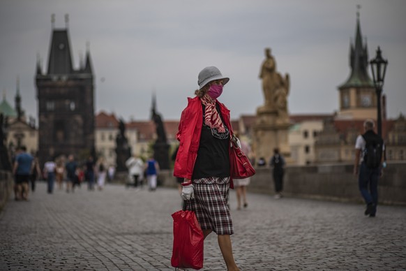 epa08691735 A woman wearing protective face mask walks on Charles Bridge in Prague, Czech Republic, 23 September 2020. Czech Republic had record rise in COVID-19 disease caused by the SARS-CoV-2 coron ...