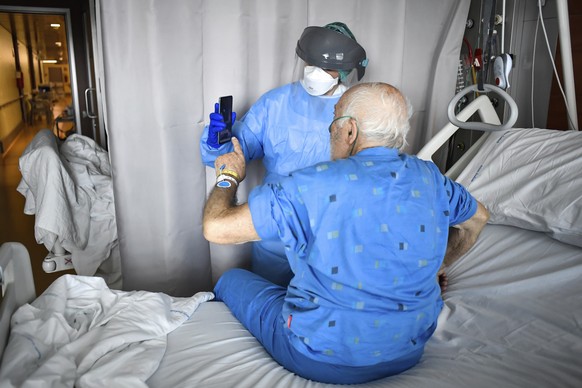 A medical staffer holds up a phone in front of a Covid-19 patient for a video call with relatives at Bergamo&#039;s Papa Giovanni XXIII hospital, northern Italy, Friday, April 3, 2020. The new coronav ...