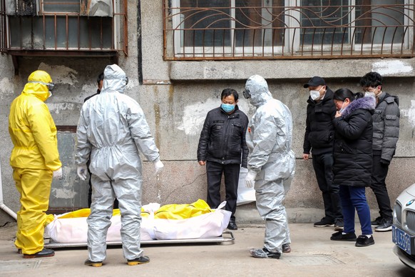 epa08187325 Funeral house workers take the body of a resident, who reportedly died because of the novel coronavirus (2019-nCoV) at home, out of a residential building in Wuhan, in central China&#039;s ...