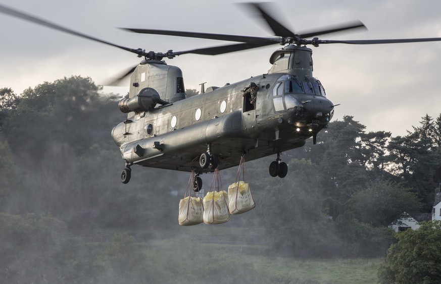 epa07754118 A handout picture provided by the British Ministry of Defence showing a British Royal Air Force Chinook Mk6a helicopter approaches with the load to drop on the dam in Whaley Bridge, Derbys ...