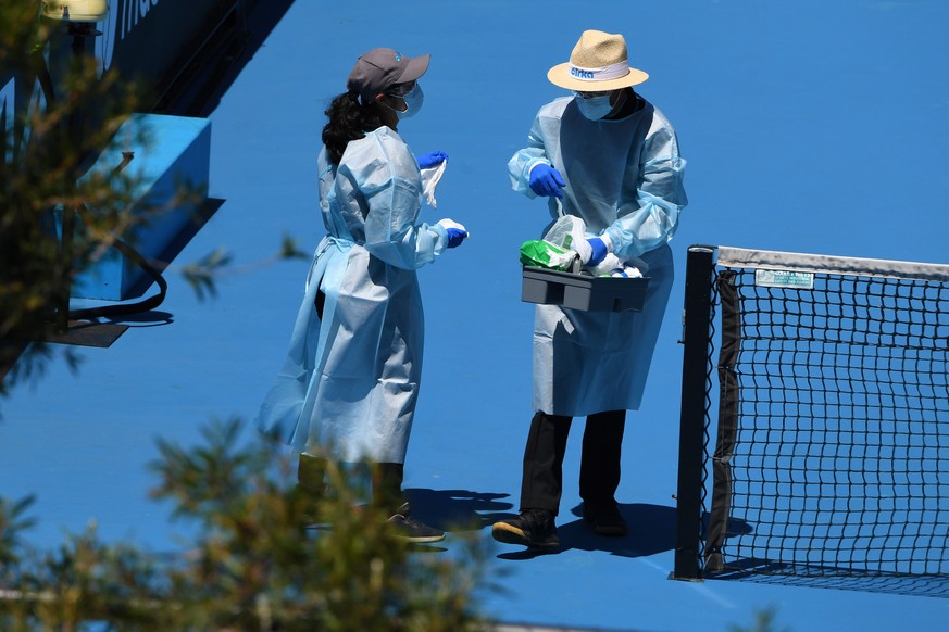 epa08956834 People wearing personal protective equipment are seen disinfecting a tennis court after a training session at Melbourne Park in Melbourne, Australia, 22 January 2021. Players who were aboa ...