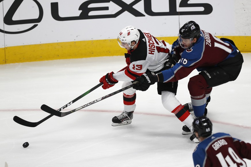New Jersey Devils center Nico Hischier, left, fights for control of the puck with Colorado Avalanche defenseman Nikita Zadorov in the first period of an NHL hockey game Friday, Dec. 13, 2019, in Denve ...