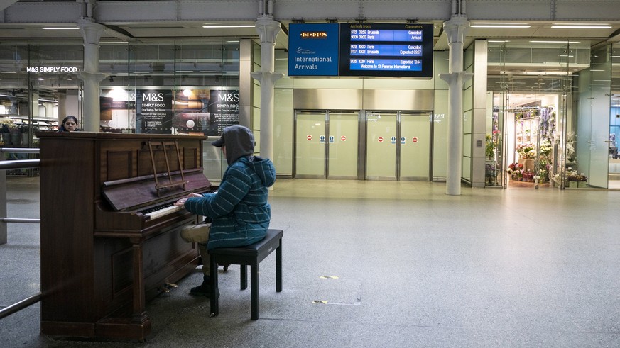 epa08303102 A person plays a piano at King&#039;s Cross St Pancras Station in central London, Britain, 18 March 2020. Transport links between the United Kingdom and mainland Europe, including the Euro ...