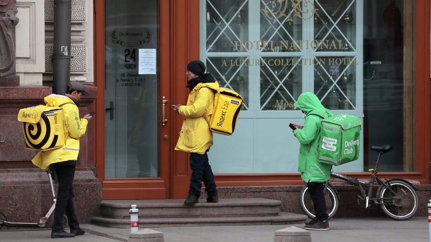 epa08332234 Russian food couriers wait outside a restaurant to pick up requested food in Moscow, Russia, 30 March 2020. The Russian government has approved amendments to tighten liability for quaranti ...