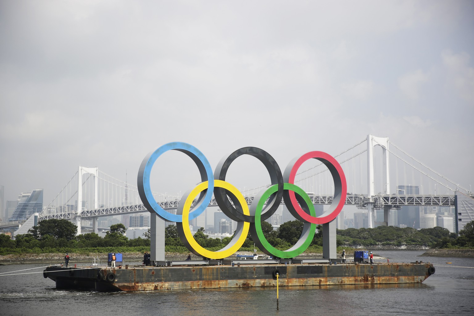 FILE - In this Aug. 6, 2020, file photo, the Olympic rings for the Olympic and Paralympic Games Tokyo 2020 pass by on a barge by tugboats off the Odaiba Marine Park in Tokyo. Tokyo Olympic officials s ...