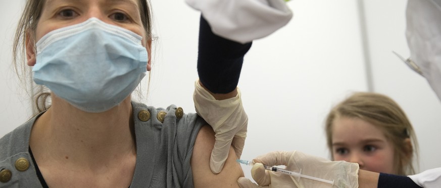 Un membre du staff medical vaccine une femme a l&#039;aide du vaccin Moderna contre le coronavirus COVID-19, lors du premier jour d&#039;ouverture du Centre de vaccination de Palexpo, ce lundi 19 avri ...