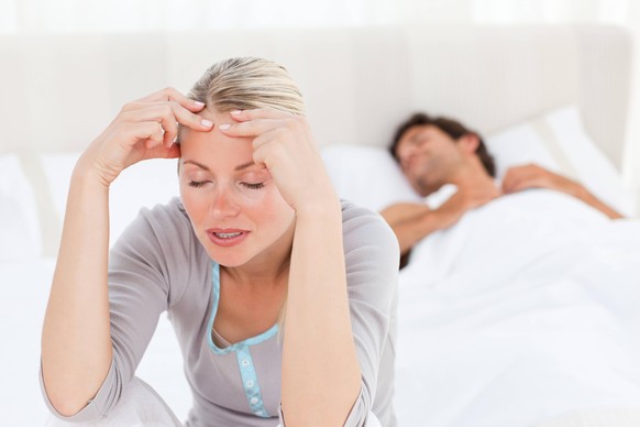 Attractive woman having a headache while her husband is sleeping Attractive woman having a headache while her husband is sleeping at home, model releasedache, adult, beautiful, bed, bedroom, caucasian ...