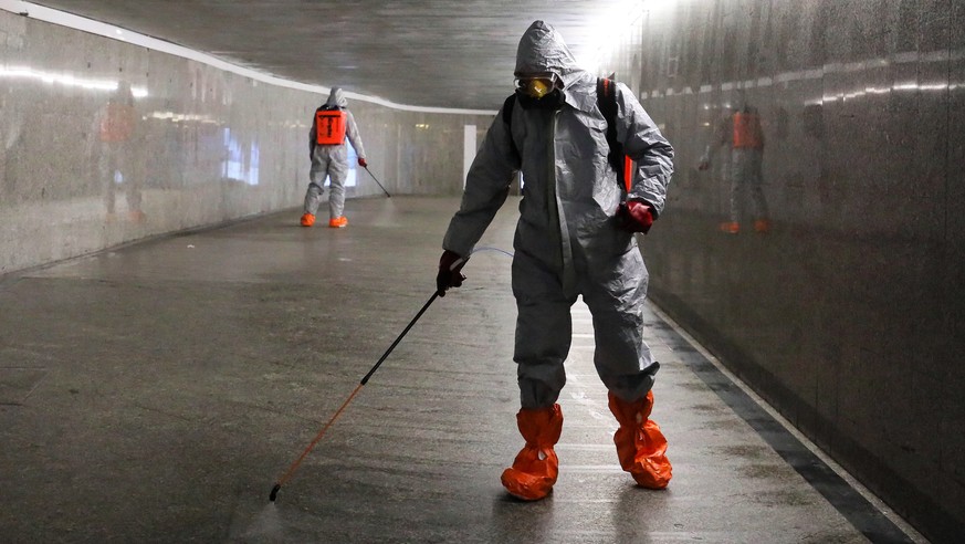 epa08339732 Workers wearing protective suits spray disinfectant at the Centrum subway station in Warsaw, Poland, 02 April 2020, amid the ongoing coronavirus COVID-19 pandemic. Countries around the wor ...