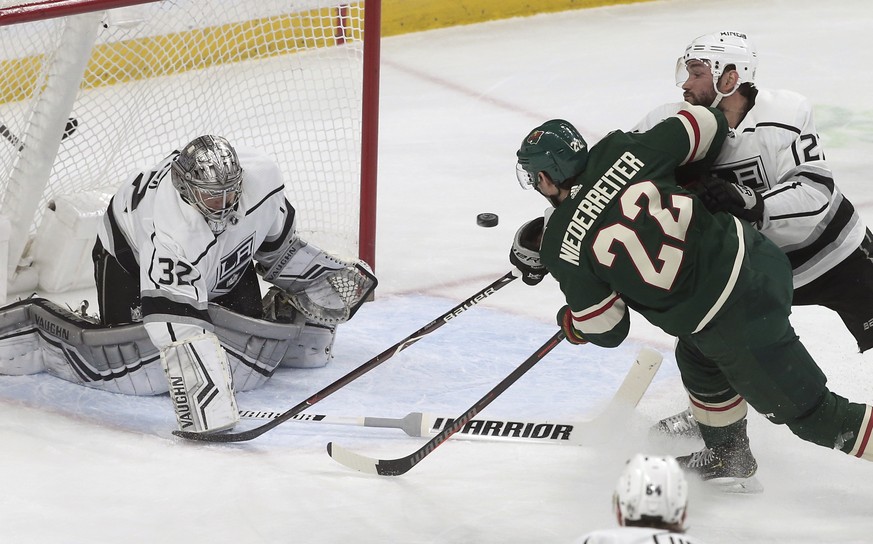 Los Angeles Kings goalie Jonathan Quick, left, deflects a shot by Minnesota Wild&#039;s Nino Niederreiter of Switzerland as Kings&#039; Alec Martinez, right, tries to break up the scoring attempt in t ...