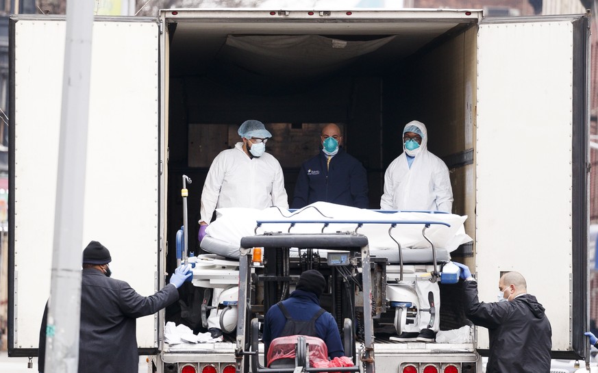 epa08333050 Medical professionals and hospital employees transfer a body on a hospital gurney into temporary storage in a mobile morgue, being used due to lack of space at the hospital, outside of the ...